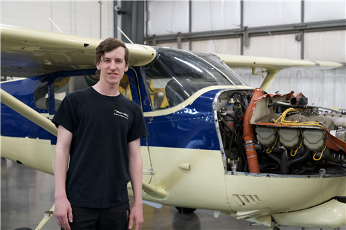 Hayden Bradley standing in front of plane in the Aviation Maintenance Technology hangar.